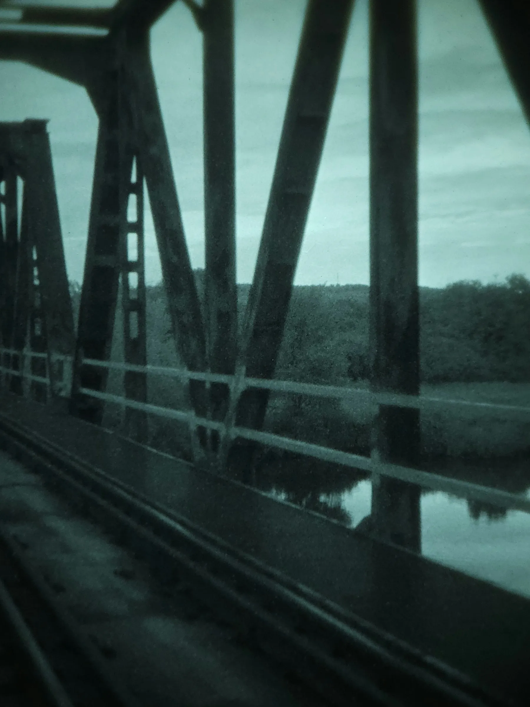 Steel bridge trusses over a river at dusk