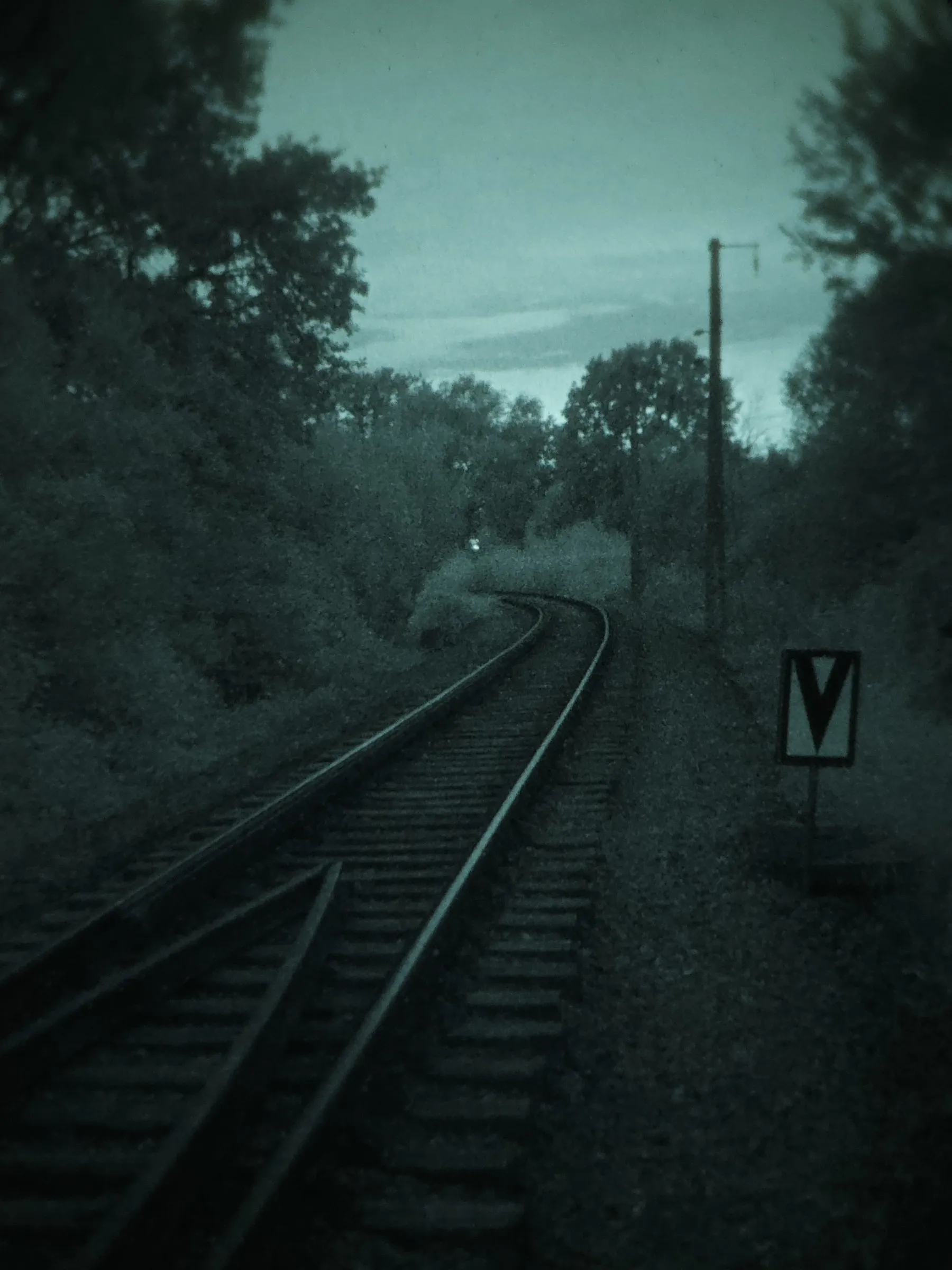 Railway warning sign beside the tracks at dusk