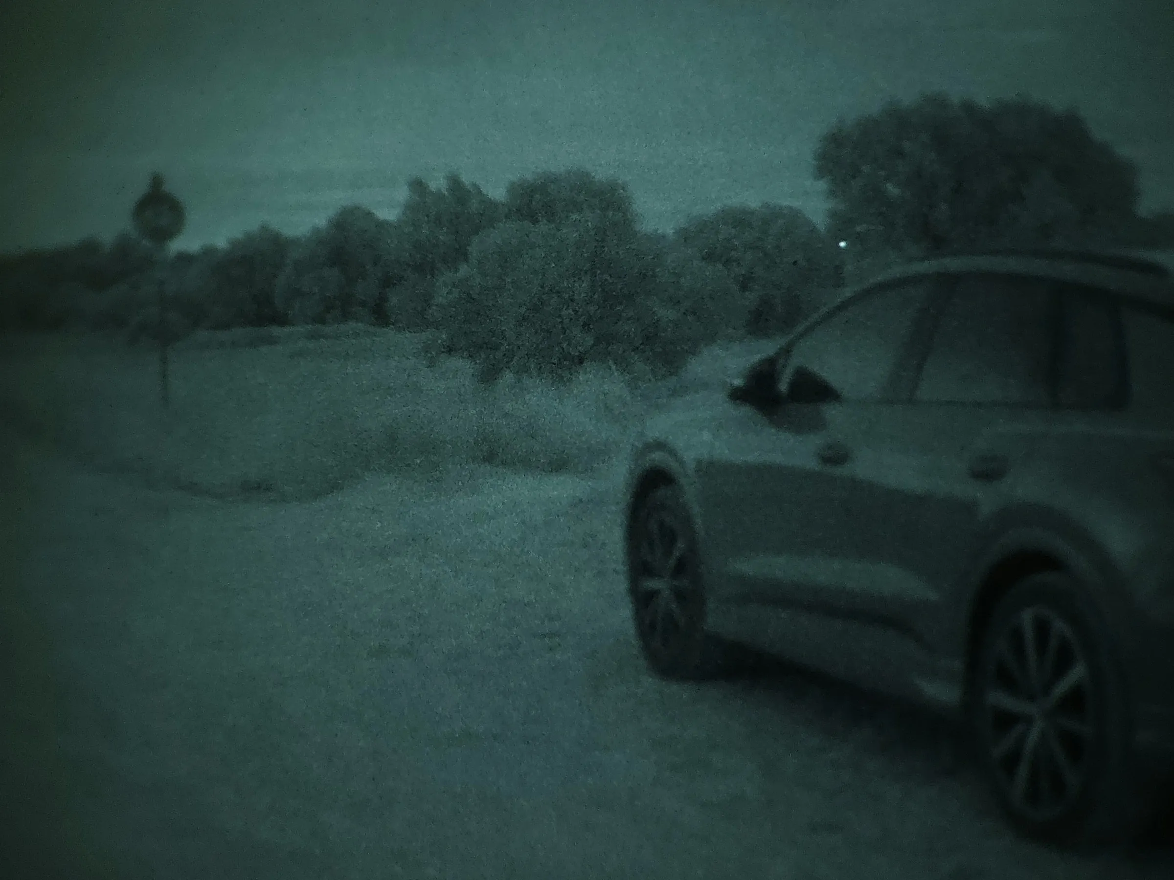 Car parked on a roadside at night, seen in night vision
